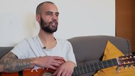 Bruno sentado en un sofá con la guitarra en la mano, durante la entrevista
