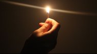 Una mano sostiene un cerillo encendido