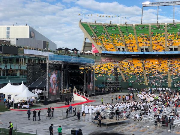 Avant la messe, au Commonwealth Stadium d'Edmonton, des gens assis, ça et là dans le stade.