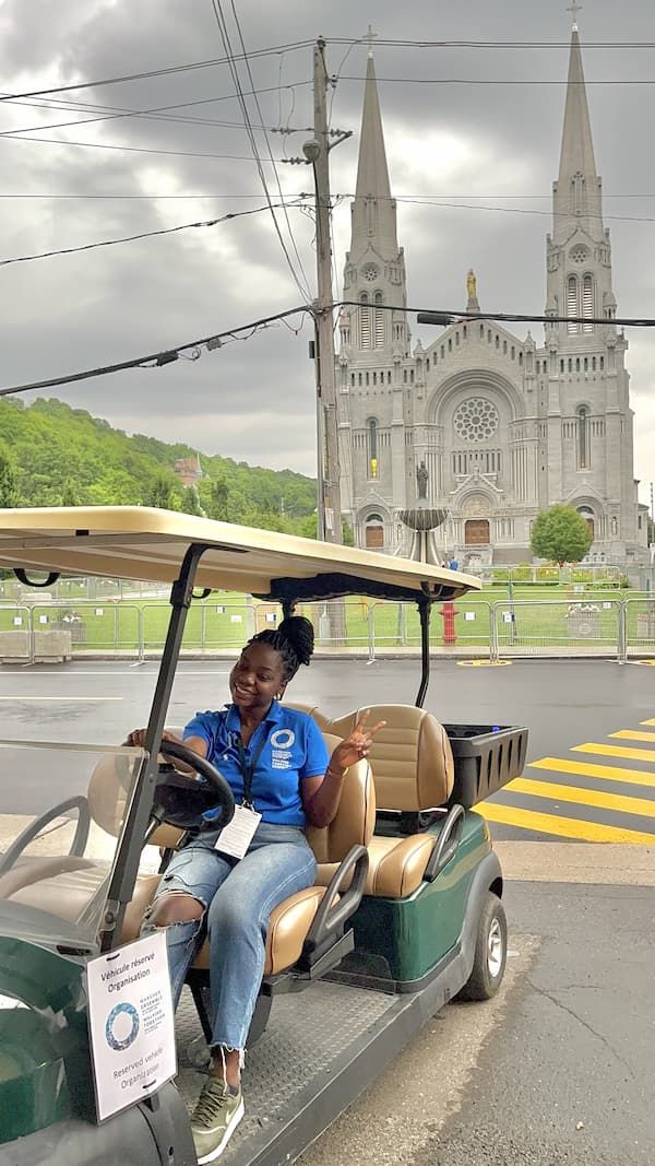 Gracia sitting in a golf cart in front of Sainte-Anne-de-Beaupré basilica