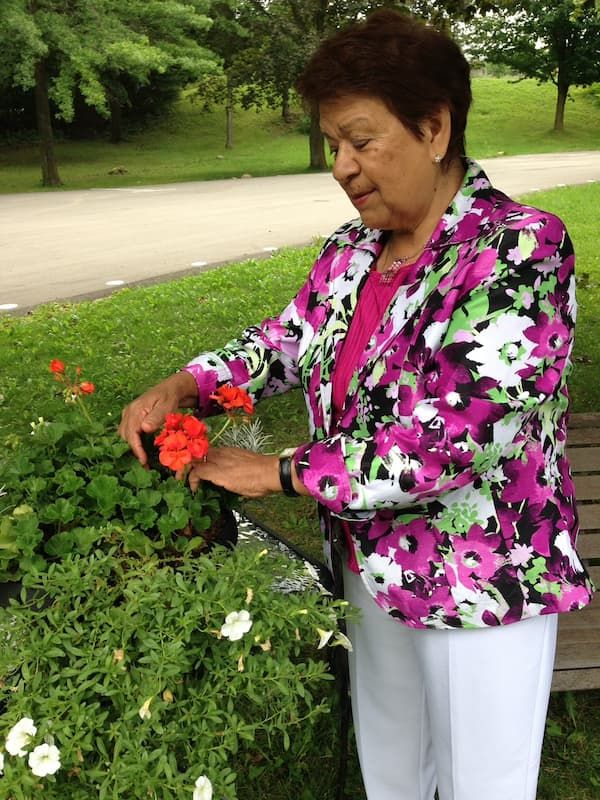 Hery, au jardin, soigne des fleurs rouges dans un pot.