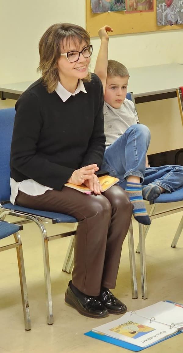 Isabelle Tremblay assise sur une chaise bleue, à l'écoute et souriante.