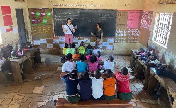 Dos voluntarias dando clase a unos niños en una escuela de Kenia.