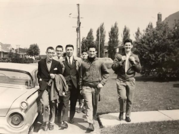 Photo 1963, noir et blanc, 6 jeunes hommes sur un trottoir, près d'une voiture. L'abbé Blais, alors laïque, est au centre.