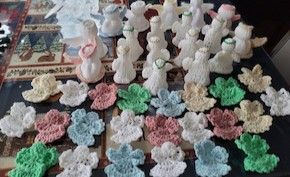 Figurines and crochet patterns in various colors are arranged on a table, showcasing meticulous craftsmanship.