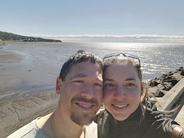 En selfie, sur un quai en béton, Marjorie et son mari. À l'arrière-plan on voit la marée basse.