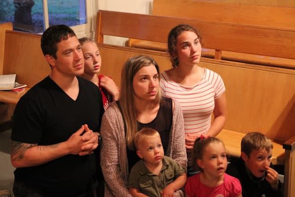 La famille, à genoux, en prière dans l'église.