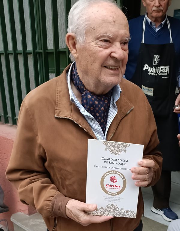 José María con el libro en la puerta del Comedor Social