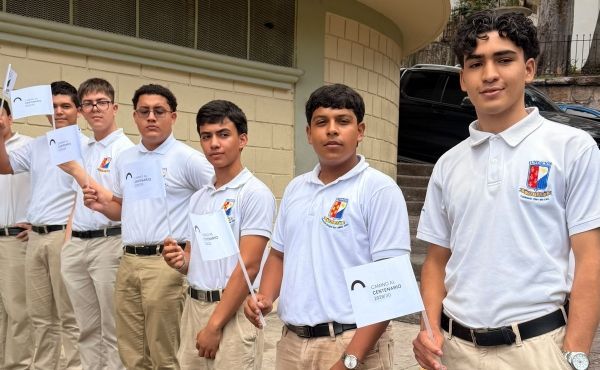 Algunos estudiantes le dieron la bienvenida al Padre fuera del salón de actos con banderitas "Camino al centenario".