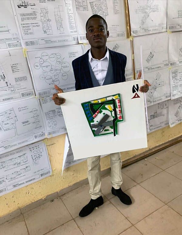 Brian, during his final presentation, standing in front of his pasted drawings, while holding the 3D model.