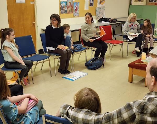 Groupe d'enfants et de parents assis en cercle sur des chaises en discussion.