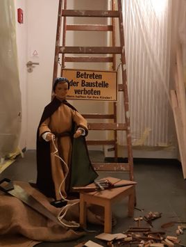 Krippenfigur des hl. Josef als Hinweis auf die Baustelle