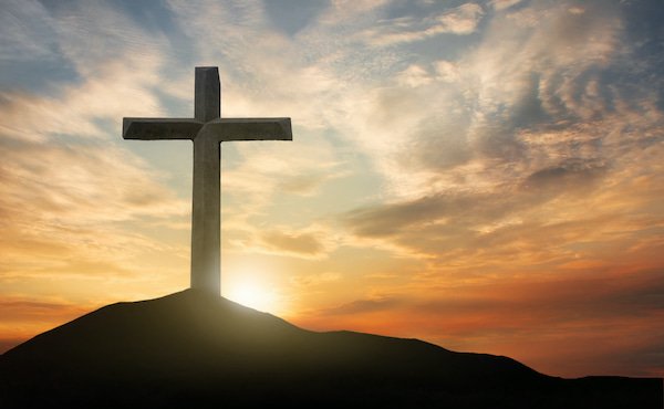 Gipfelkreuz am Berg bei stimmungsvollem Sonnenuntergang