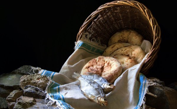 Korb mit einem Tuch und darin fünf Broten und zwei Fischen