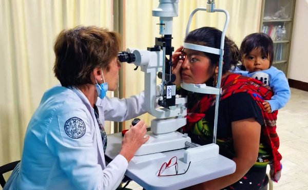 Augenärztin untersucht die Augen einer Mutter mit Kleinkind