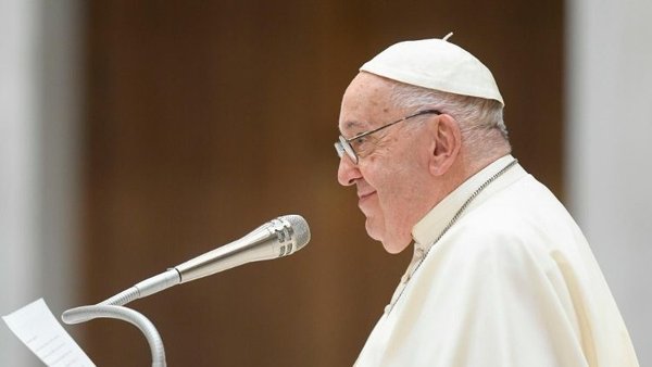Pope Francis talking in front of a mic, view from the left